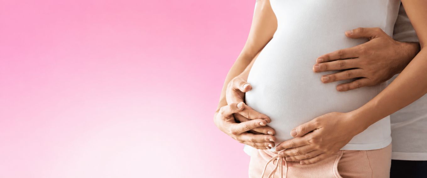 Pregnant woman with partner gently holding her baby bump